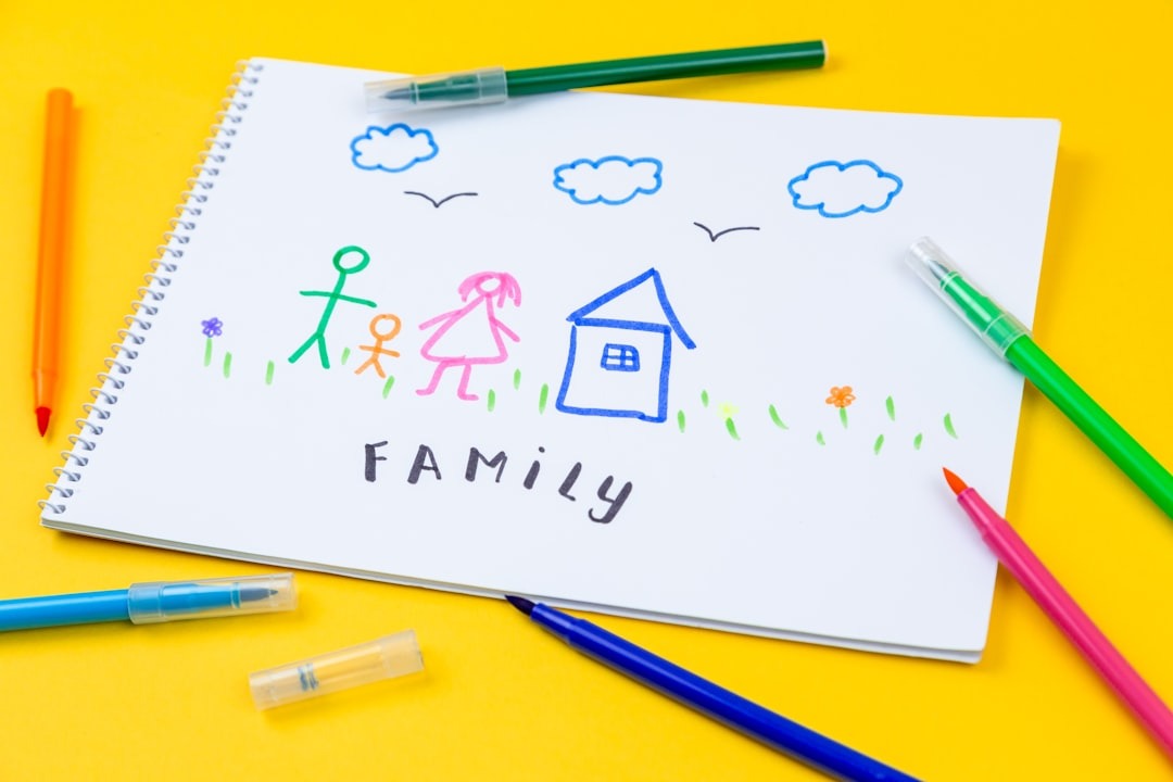 Child's drawing of family on notepad surrounded by markers.